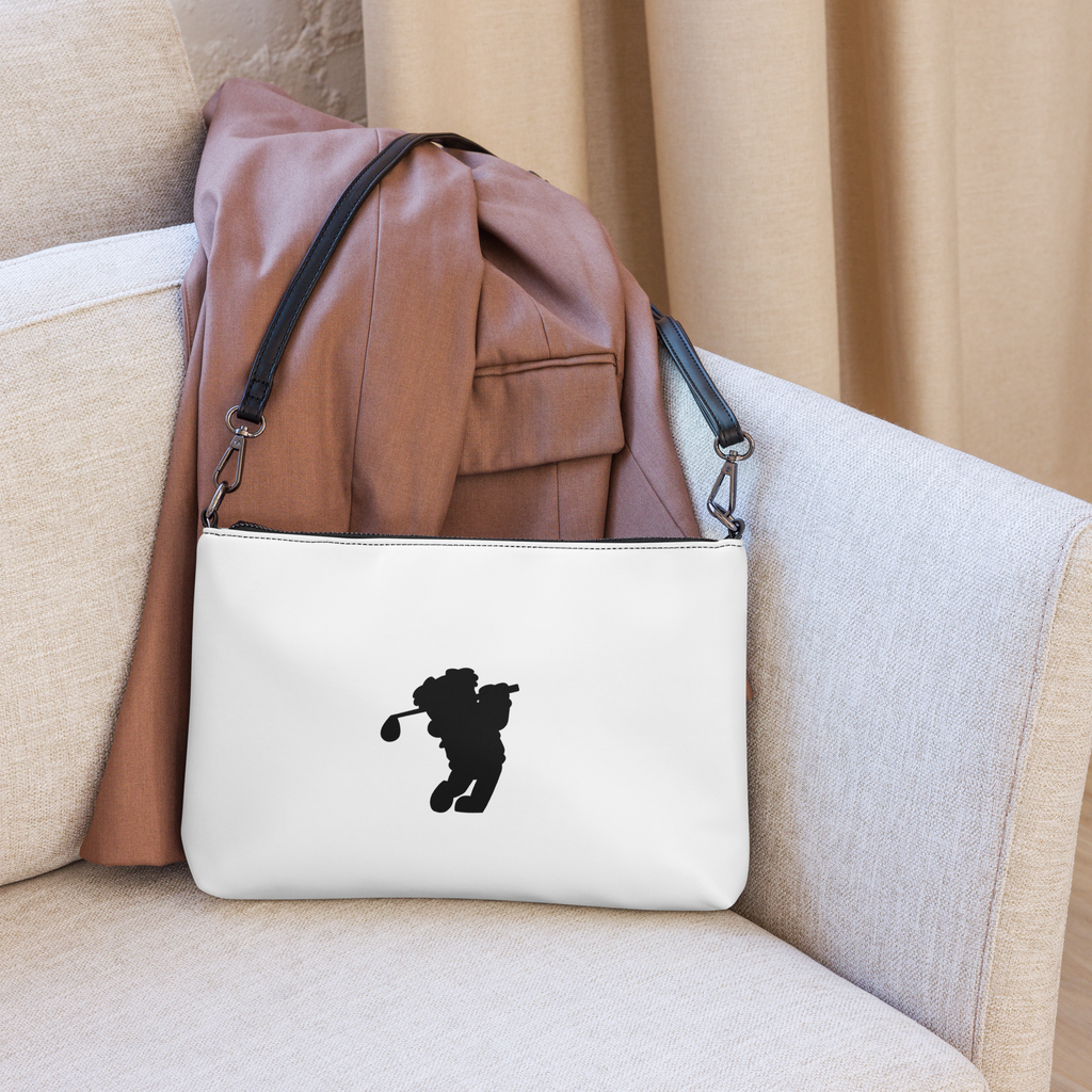White pouch with a black silhouette of a person holding a golf club on a beige couch, with a brown leather backpack on top.