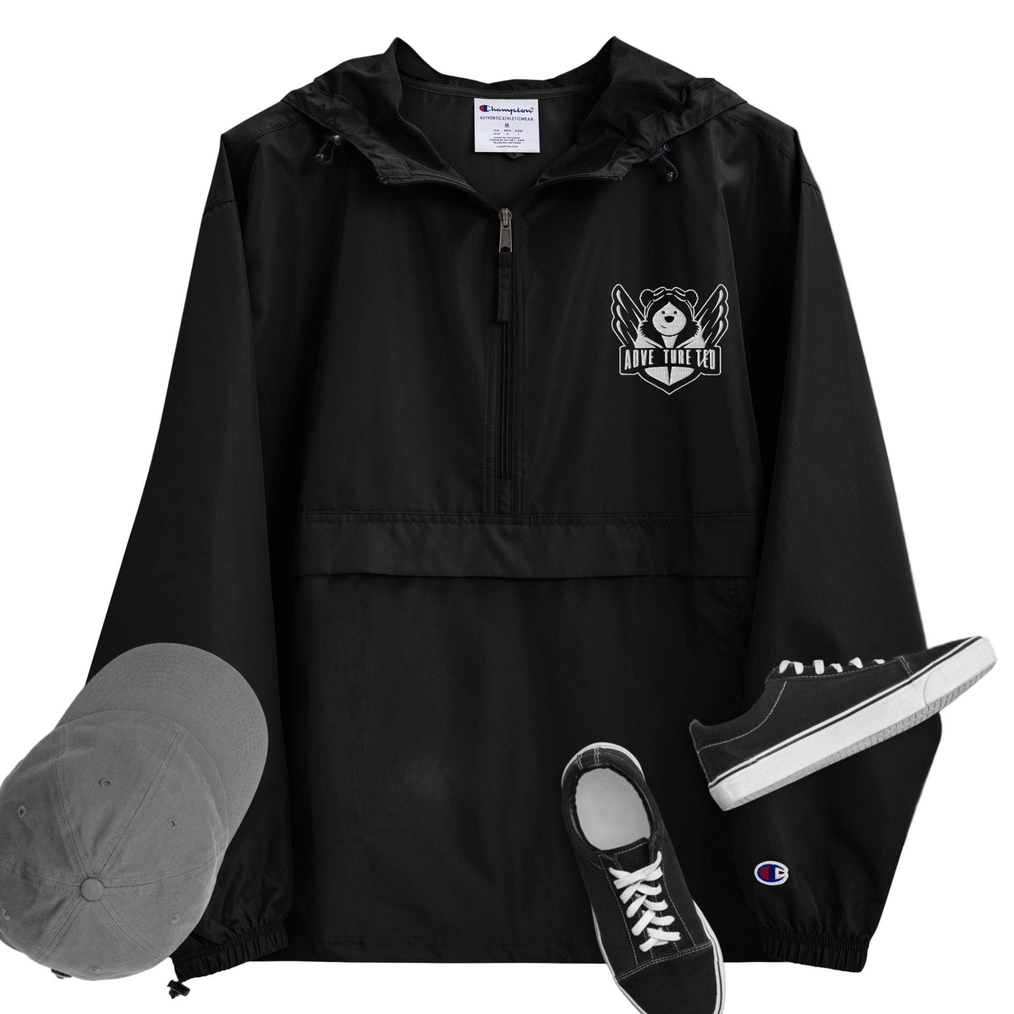 A black packable jacket with embroidered 'C' logo on the left sleeve, a hood, front kangaroo pocket, and a zipped pouch pocket. It is displayed alongside a grey hat and black sneakers.