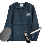 A navy packable jacket with embroidered 'C' logo on the left sleeve, a hood, front kangaroo pocket, and a zipped pouch pocket. It is displayed alongside a grey hat and black sneakers.