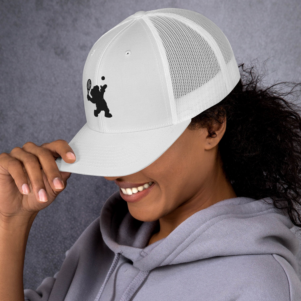 Person wearing a white cap with a black logo against a gray background