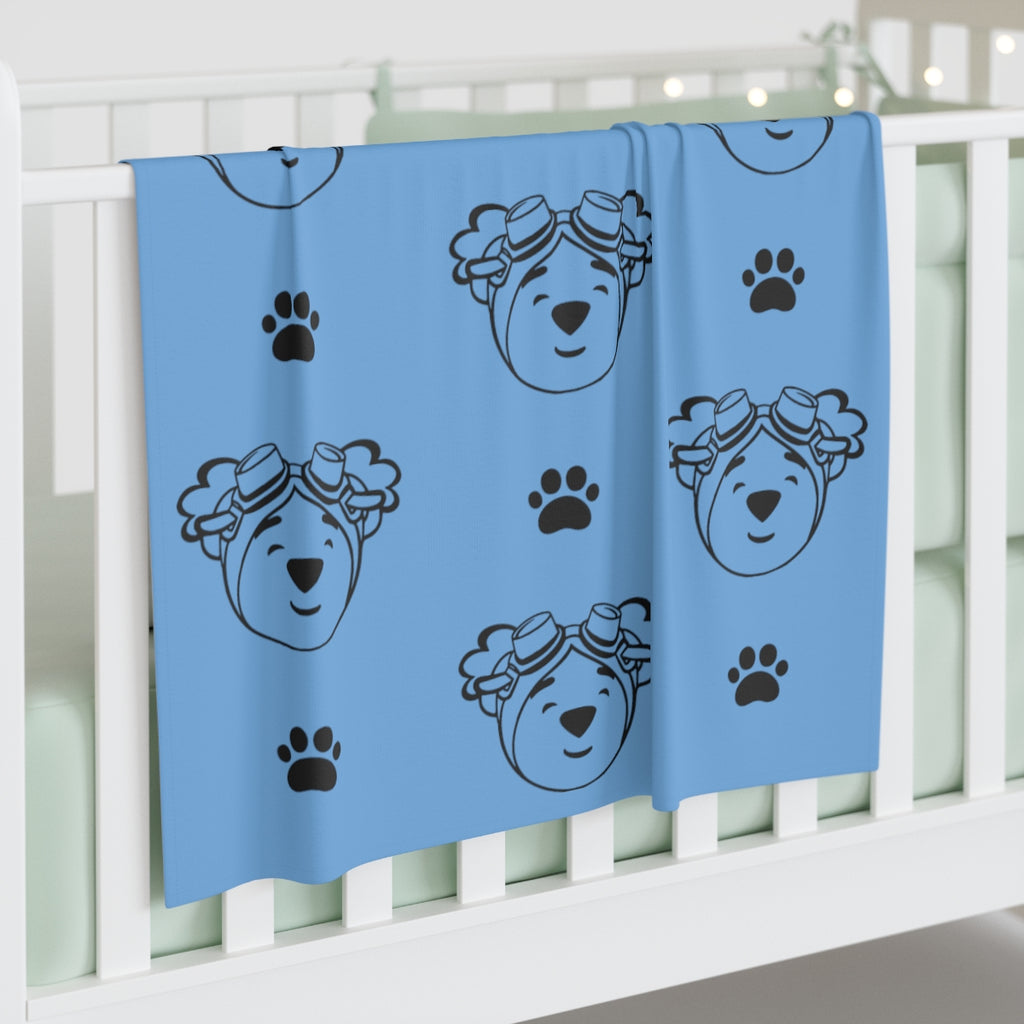 Light blue jersey blanket with paw prints and outline of adventure ted face. 