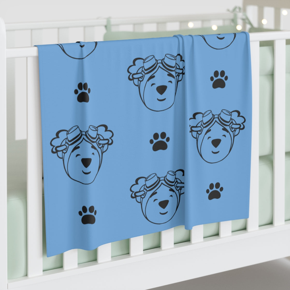Light blue jersey blanket with paw prints and outline of adventure ted face. 